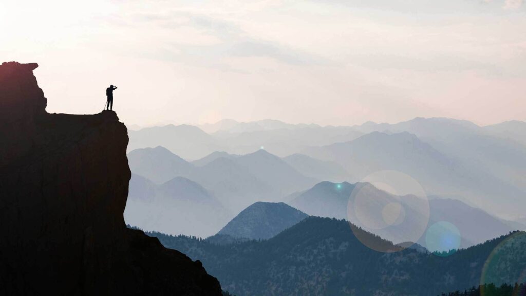 Traveler standing on cliff looking into the mountains