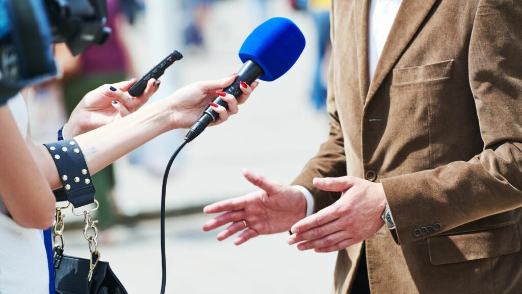 a woman filming an interview video with a blue microphone