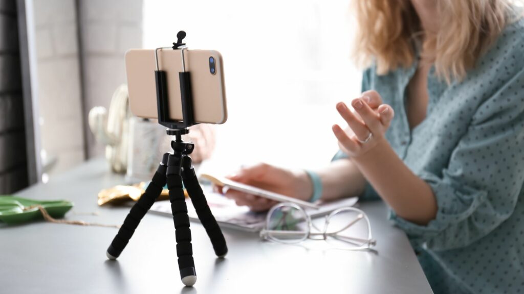 woman uses a smartphone and tripod for remote video recording