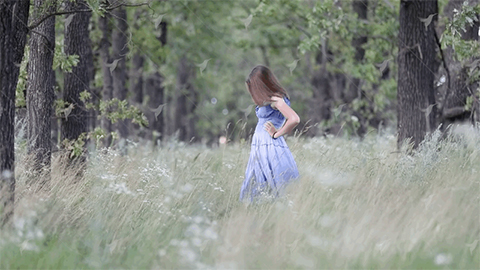 woman in a purple dress stands in a field of grass